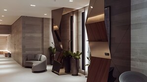 A modern interior with a sofa, potted plants, and a unique geometric wall design. - SOMA PERDIZES 908 (São Paulo)