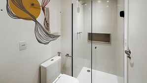 A modern bathroom with a glass shower enclosure, a toilet, and a wall-mounted sink. - SOMA PERDIZES 908 (São Paulo)