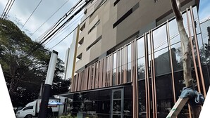 A modern building with large windows and a glass facade, a white van parked in front, and a ladder leaning against the building. - SOMA PERDIZES 908 (São Paulo)