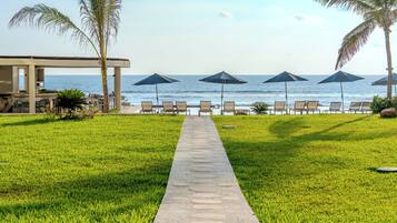 A pathway leading to beach chairs and umbrellas, with a view of the ocean.