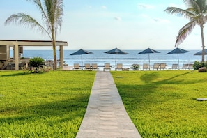 A pathway leading to beach chairs and umbrellas, with a view of the ocean. - Depto. Frente al Mar. Acapulco 4 Rec (Acapulco)