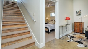 A staircase with wooden steps and a handrail, leading to a bedroom with a bed, bedside table, lamp, and a cabinet. - Quiet / River / Bike Bath (Salida)