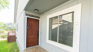 A house with a wooden front door, a sign above it reading "BIENVENIDOS", and a large window to the right. - Lux Home MINS to NE Baptist Hospital & TPC San Antonio/ Sleeps 4 (San Antonio)