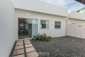 Une maison moderne dotée d’un patio, d’un petit jardin et d’une allée gravillonnée.