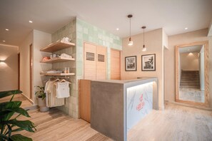 Een receptiegedeelte met een houten receptiebalie, een wandplank met opgevouwen kleding, en een lijst met een foto aan de muur.