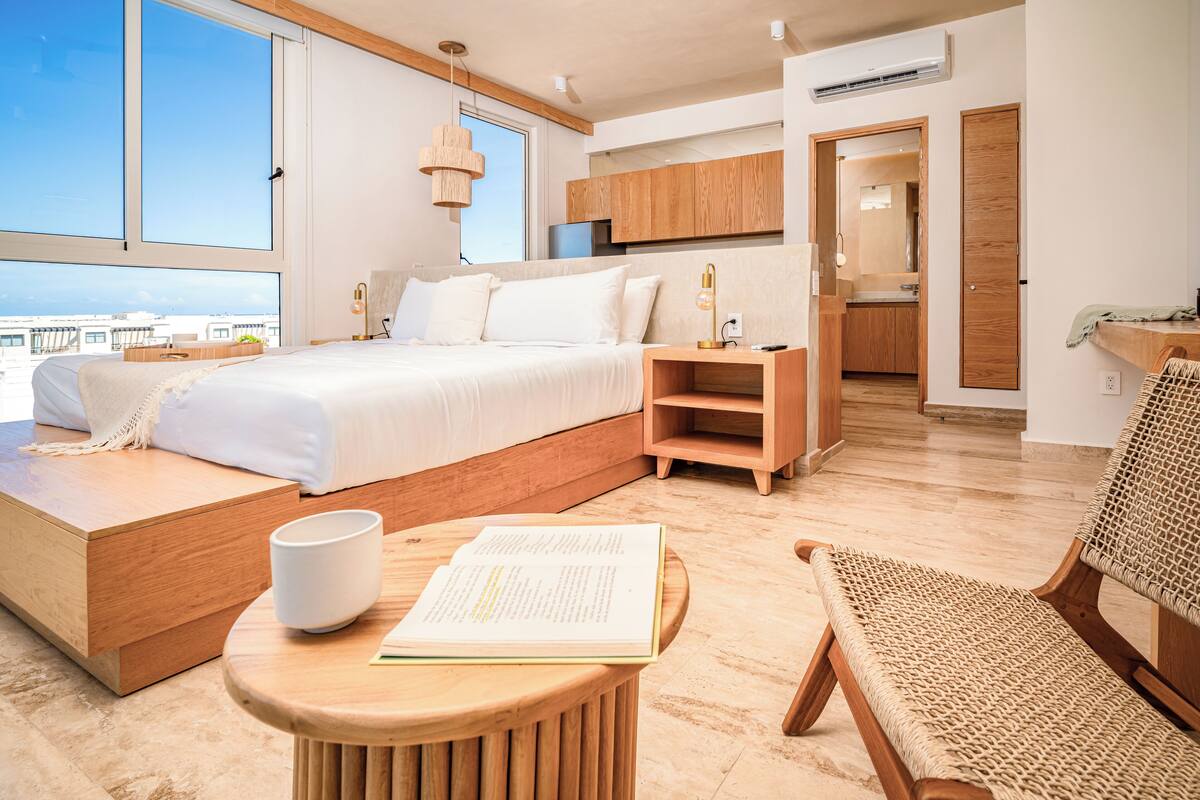 A modern bedroom with a large bed, wooden furniture, and a view of the city.