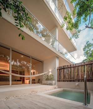 Un edificio moderno con piscina, asientos exteriores y una hamaca.