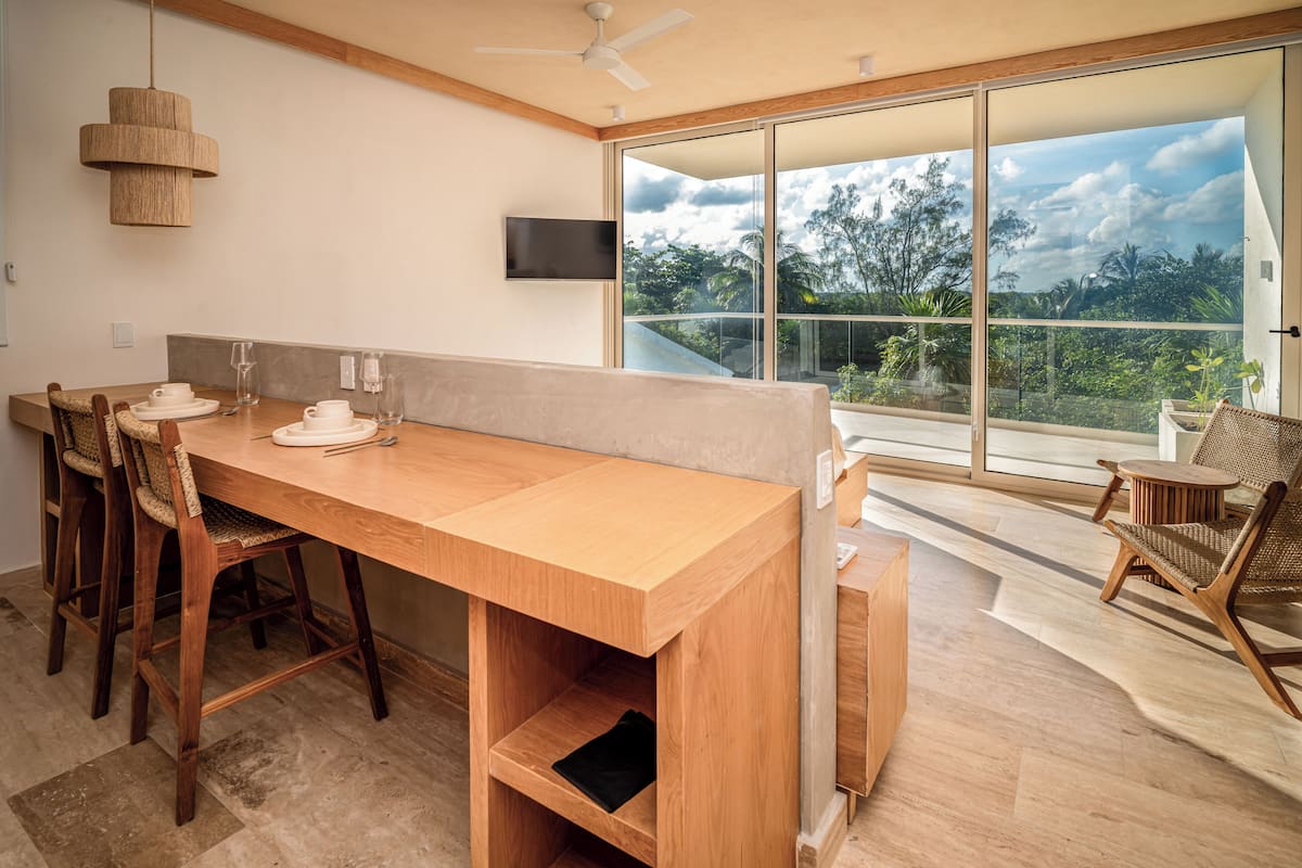A modern dining area with a wooden table, chairs, and a large window offering a view of the outdoors.