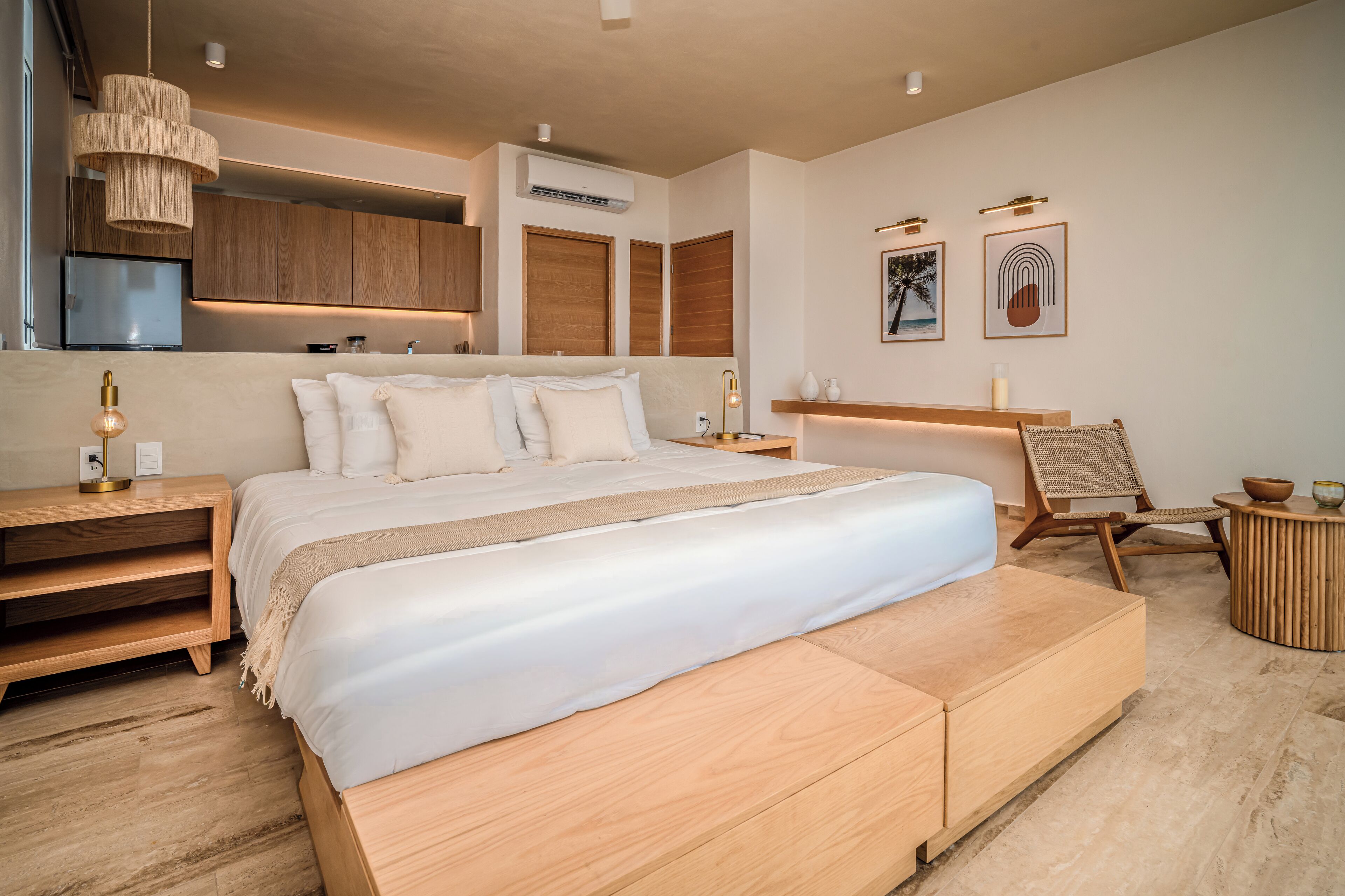 Ein modernes Schlafzimmer mit einem großen Bett, einem Holz-Kopfstück, Nachttischen, einem Sessel und einem kleinen runden Tisch.