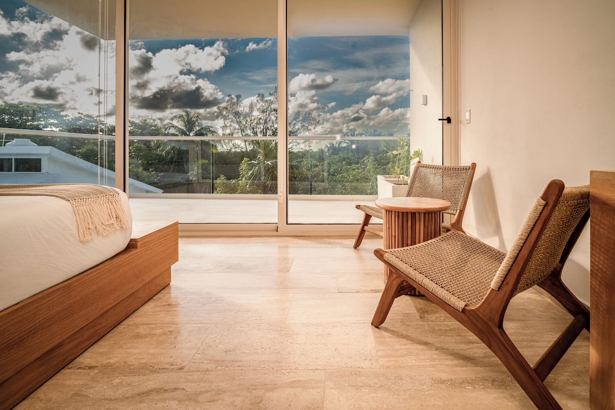 A modern bedroom with a large window, a bed, a chair, and a small table.