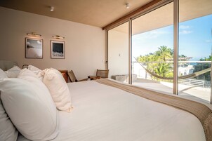 A spacious bedroom with a large bed, a view of the outdoors, and two framed pictures on the wall.