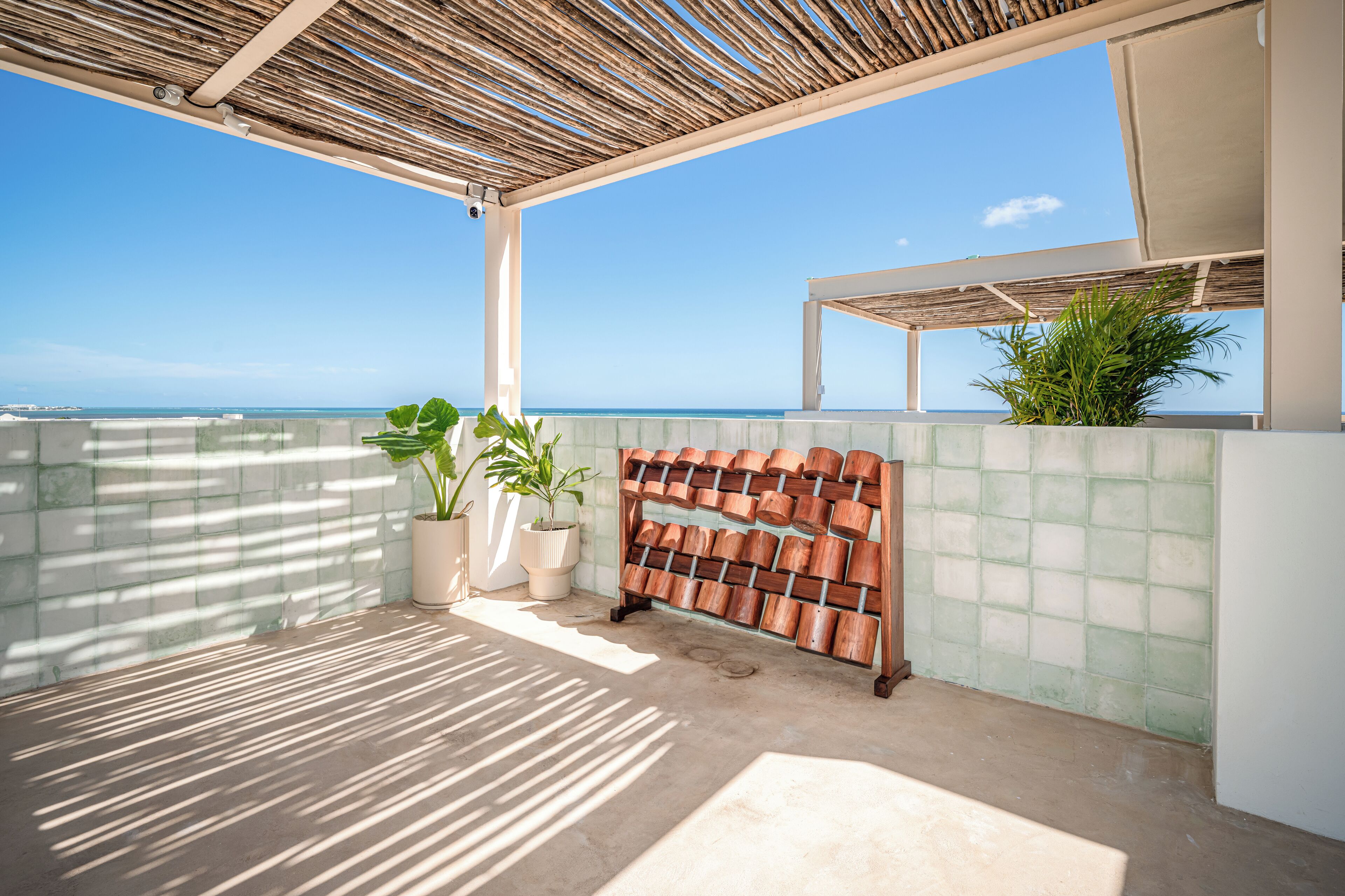 Ein überdachter Außenbereich mit Blick auf das Meer, Kübelpflanzen und eine Wand aus Holzpflanzkästen.