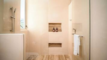 Un baño moderno con cabina de ducha de vidrio, un estante empotrado con artículos de aseo y un perchero para toallas.