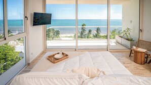 Un dormitorio con una cama grande, televisor y vista al océano.