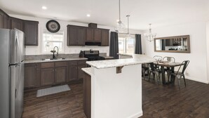 Eine moderne Küche mit dunklen Holzschränken, einem Edelstahlkühlschrank und einer zentralen Kochinsel.