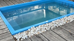 A rectangular pool with a blue border, surrounded by white pebbles and wooden decking. - Mountain cabin, natural environment, Huequecura river tourist attractions (Santa barbara)