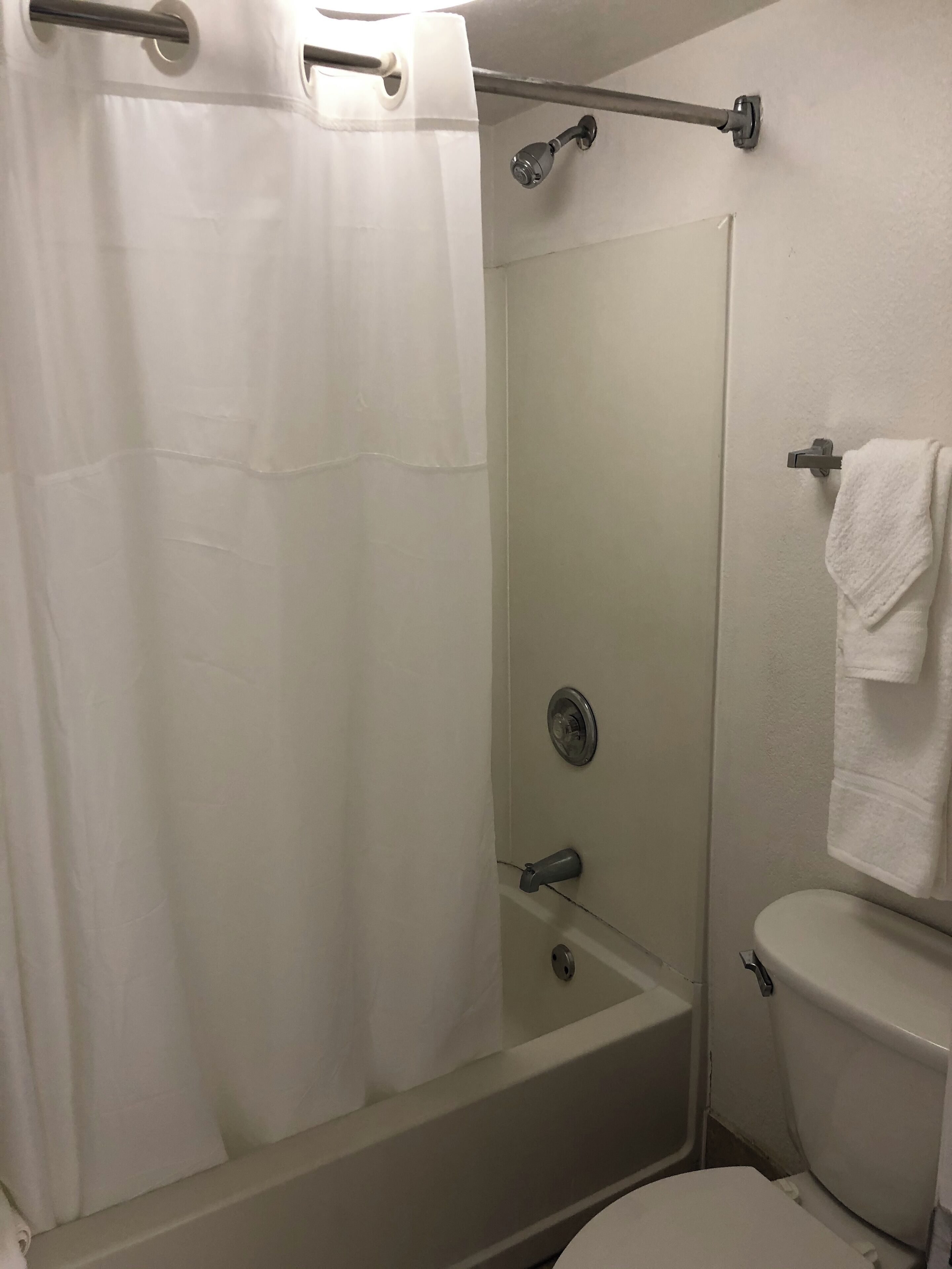 Un baño con ducha, inodoro y perchero para toallas.