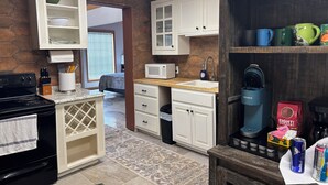 A compact kitchen with white cabinets, a microwave, a kettle, and a coffee maker.