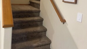 A carpeted staircase with wooden handrails and a framed leaf artwork on the wall. - Cozy Home in Beaverton (Aloha)