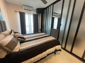 Ein modernes Schlafzimmer mit einem großen Bett, gestreifter Bettwäsche und Blick ins Freie durch eine Schiebetür.