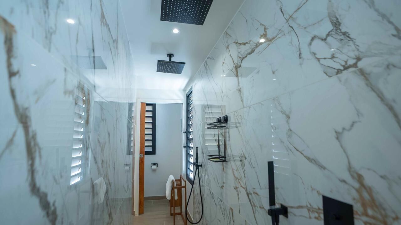A modern bathroom with marble walls, a shower area, and a towel rack.