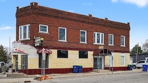 A two-story brick building with a storefront, a sign for liquor and beer, and a closed awning.