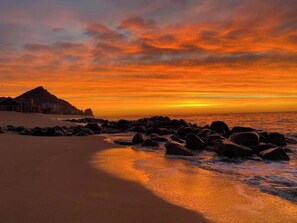 Een strand met een rotsachtige kustlijn en een berg op de achtergrond.
