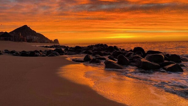A beach with a rocky shoreline and a mountain in the background. - Lujoso con una habitación y vista al mar (Cabo San Lucas)