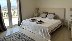 Un dormitorio con cama, mesita de noche, lámpara, ventilador de techo y vistas a través de un puertas correderas.