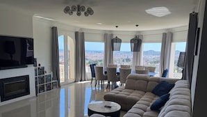 Una sala moderna con sofá, televisor, chimenea y vistas a la ciudad.
