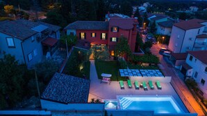 Ein Wohngebiet mit Swimmingpool, Liegestühlen und einem roten Haus mit vielen Fenstern.