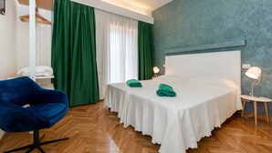 Ein Hotelzimmer mit Bett, Sessel, Tisch und Lampe.