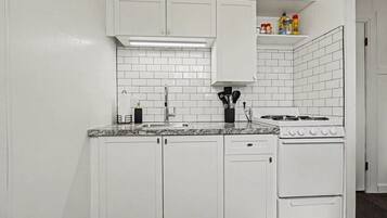 Una cocina con gabinetes blancos, encimera de granito, estufa y lavaplatos.