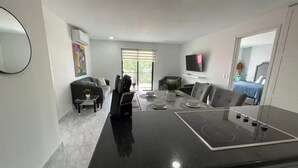 A modern kitchen with a central island, dining table, and seating area. - Condominio de 2 dormitorios y 2 baños, piscina y parrilla en Cabo San Lucas (Cabo San Lucas)