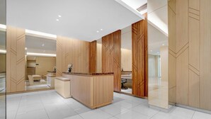 A modern hotel lobby with a reception desk, wooden paneling, and a tiled floor. - OYO 95052 Cordia Tower (Gunung Putri)
