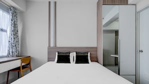 A hotel room with a bed, a desk, a chair, and a wardrobe. - OYO 95052 Cordia Tower (Gunung Putri)