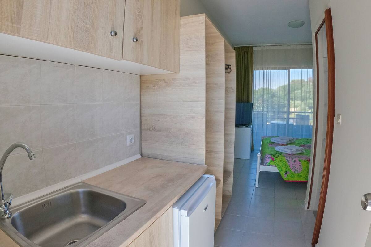 A modern kitchen with a built-in sink, a compact dishwasher, and wooden cabinets.