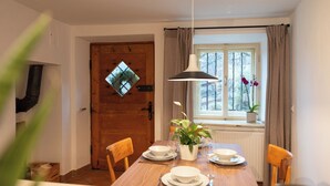 A dining area with a wooden table set for four, a potted plant, and a window with curtains. - Idyllic apartment on the Ritten - peace, nature & views of the Dolomites. Mobilcard incl (Trentino-Alto Adige)