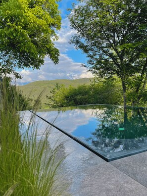An infinity pool with a clear view of a lush green landscape and distant hills. - Idyllic apartment on the Ritten—peace, nature, and views of the Dolomites. Mobilcard included (Trentino-Alto Adige)
