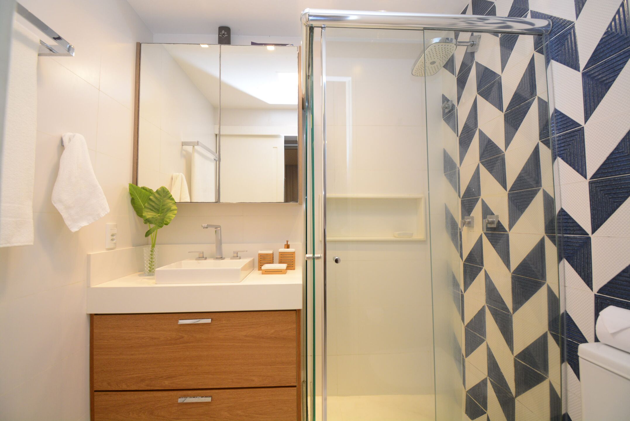 A modern bathroom with a glass-enclosed shower, a white sink, and a wooden cabinet.