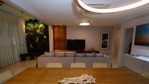 Un salon moderne avec une table à manger en bois, un canapé gris et un téléviseur à écran plat.