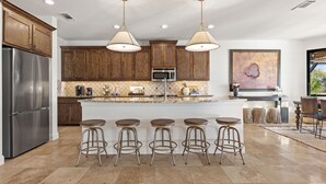Een moderne keuken met houten kastjes, roestvrijstalen apparatuur en een centraal kookeiland met barkrukken.