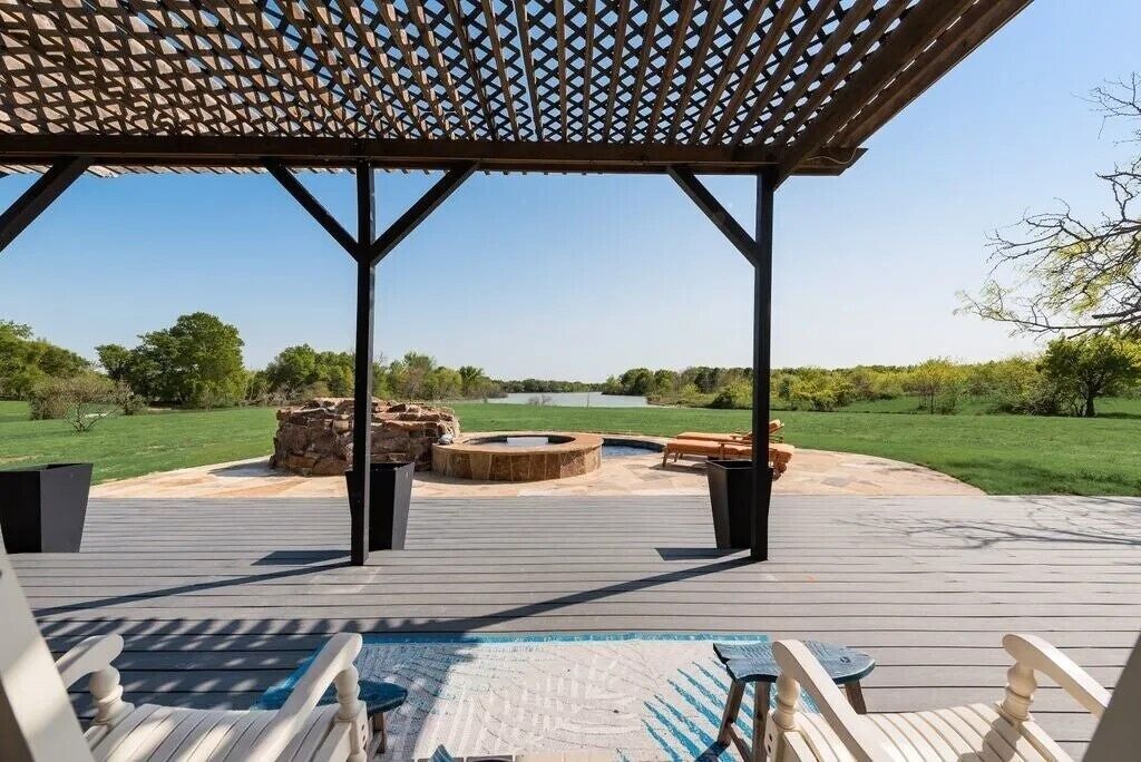 A wooden deck with a pergola, outdoor seating, and a fire pit.