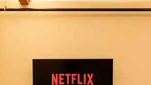 Televisão de tela plana fixada na parede, exibindo o logotipo da Netflix.