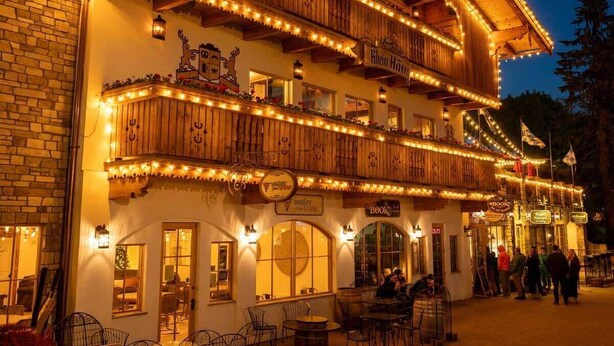 Ein zweistöckiges Gebäude mit Holzfassade, mehreren Balkonen und Lichterketten.