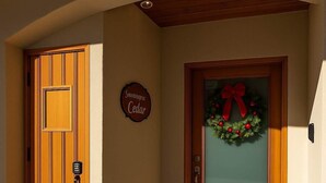 Een houten deur met een codeerapparaat, een glazen deur versierd met een rode strik en kerstkrans, en een bord met de tekst 'Sawmage Cedar'.