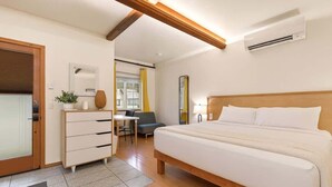 Een hotelkamer met een houten bed, een bureau, een stoel, een dressoir en een spiegel.