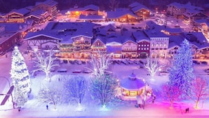 Un villaggio innevato con edifici e alberi illuminati, che evoca un'atmosfera invernale.