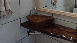 A bathroom with a wooden vanity, tiled walls, and a mirror. - Hotel Pousada Gaúcha Caibi (Caibi)