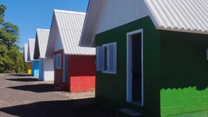 A row of colorful, single-story buildings with white roofs and a green building with a door and window. - Hotel Pousada Gaúcha Caibi (Caibi)